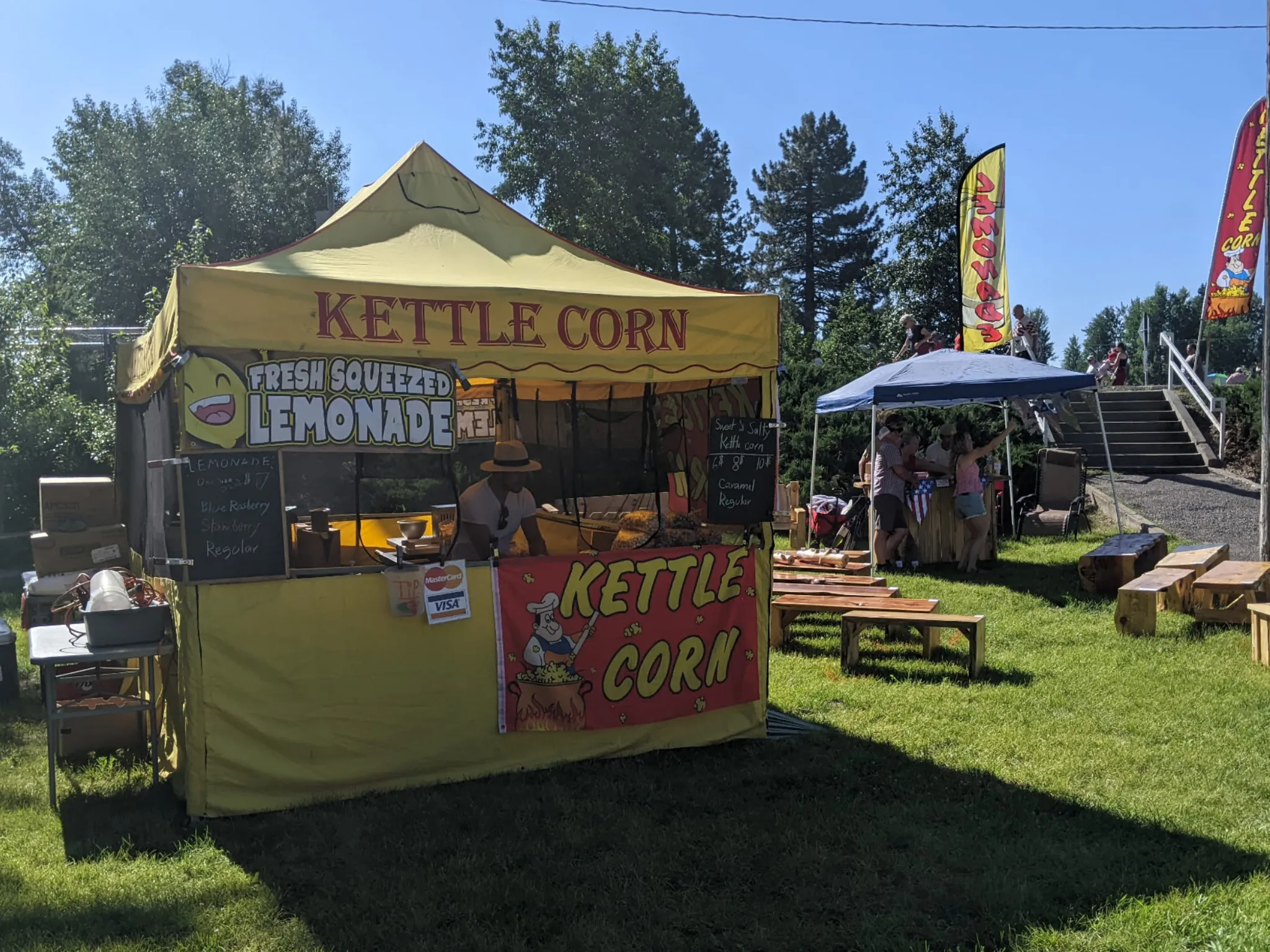 Baker's yellow kettle corn tent set up on the grass at a summer event
