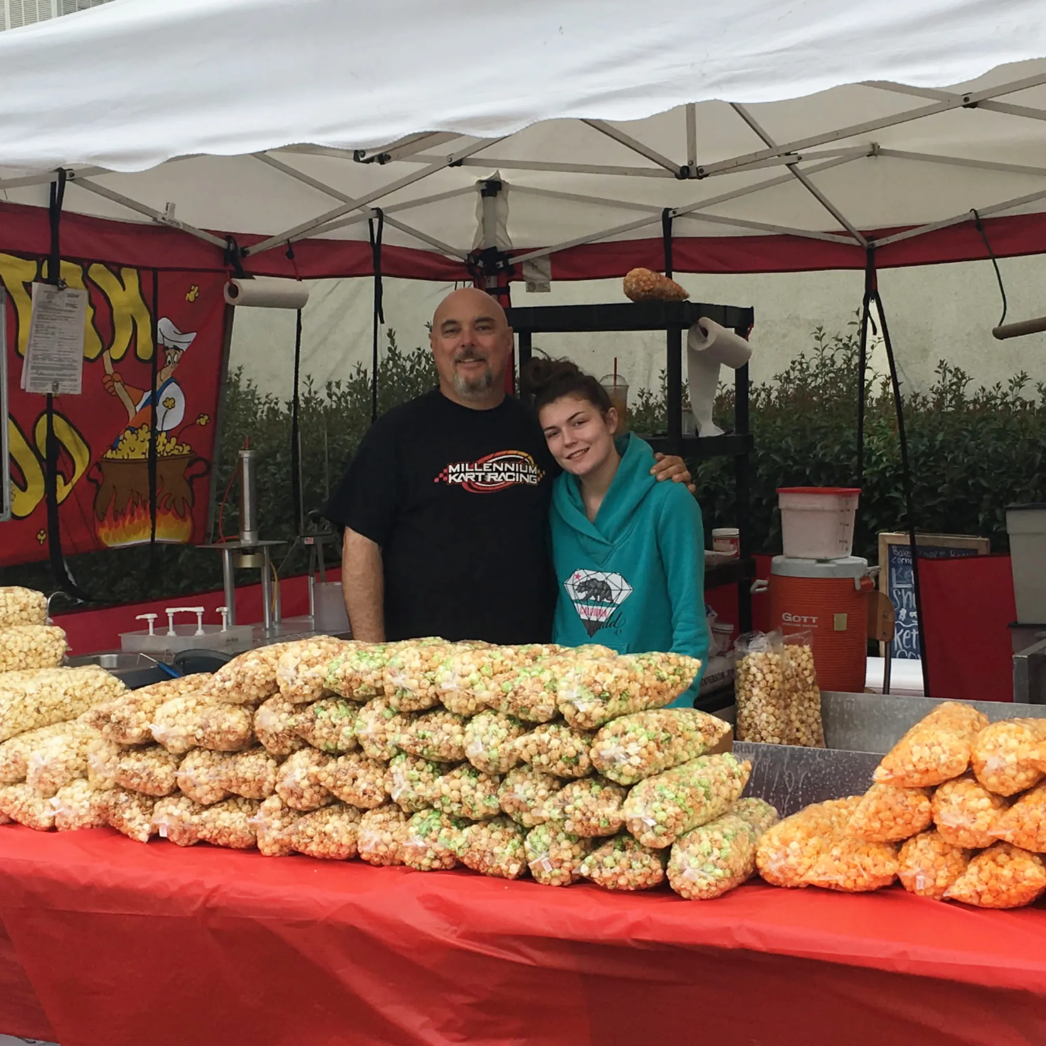 The Baker family behind a booth table loaded with bags of kettle corn